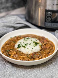 a white bowl filled with beans and rice next to an instant pressure cooker in the background