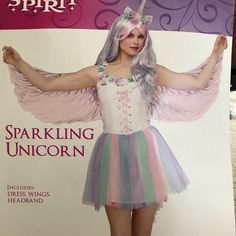 a woman in a pink and blue dress is standing with her arms spread out while wearing a unicorn costume