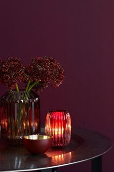 two vases with flowers in them sitting on a table next to a candle holder