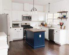 a kitchen with white cabinets and blue island