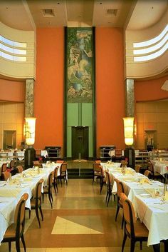 a dining room with tables and chairs in front of a large painting on the wall