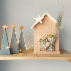 a small wooden house on top of a shelf next to christmas trees and other decorations