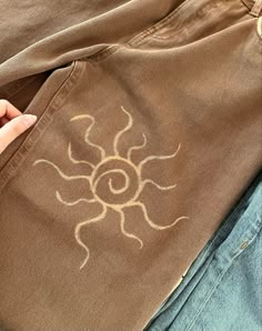 someone is holding their hand over the pocket of a pair of jeans that have sun designs on them