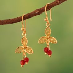 Inspired by the lotus flower, Peru's Alfredo Inga creates a striking pair of gold-plated dangle earrings that capture the beauty of this natural wonder. The earrings are adorned with vibrant carnelian beads that gracefully sway from a delicate filigree design. Each petal is skillfully crafted to perfection, resulting in a lace-like beauty that is the hallmark of this revered jewelry artistry. These accessories are finished with a refined polished sheen, which adds a touch of sophistication to their overall look. Red Lotus Flower, Filigree Hoop Earrings, Red Lotus, Carnelian Beads, Filigree Earrings, The Lotus, Filigree Design, Lovely Earrings, Silver Filigree