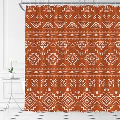 a shower curtain with an orange and white geometric pattern on it, next to a chair