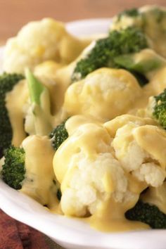 a white bowl filled with broccoli and dumplings covered in yellow cheese sauce