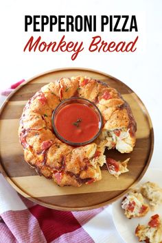 pizza monkey bread on a wooden plate with sauce in the middle and other food items around it