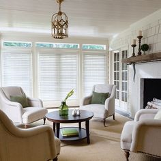 a living room filled with furniture and a fire place in front of a window covered in blinds