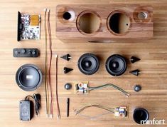 speakers, wires, and other electronics are laid out on a wooden floor with the speaker plugged in