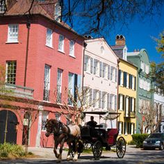 a horse drawn carriage on the street in front of some buildings with cars parked nearby