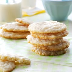 several cookies stacked on top of each other near a glass of milk and a blue cup