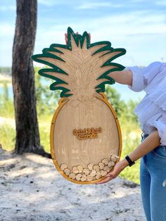 a woman holding up a wooden cutout of a pineapple with peanuts in it