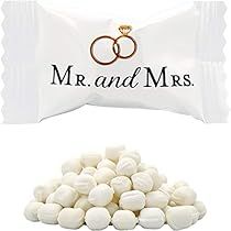 a white candy bar with two wedding rings on it next to a pile of marshmallows