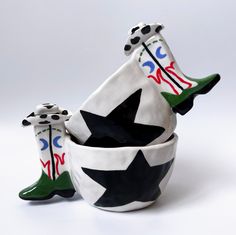 three ceramic vases with black and white designs on them, one is holding a green boot