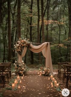 an outdoor wedding ceremony with candles and flowers on the aisle, surrounded by tall trees