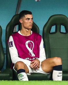 a soccer player sitting on the sidelines with his foot up in front of him