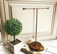 a bonsai tree in a pot next to a book on the ground with a chain hanging from it