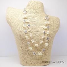 a white necklace with pearls and crystals on a mannequin headpiece for display