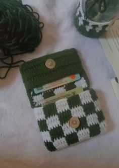 two green and white crocheted purses sitting on top of a bed next to yarn