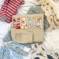 various baby clothes are laid out on a bed with the word mama spelled in letters