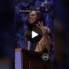 a woman standing at a podium with her hand up in front of her face and the words women behind her