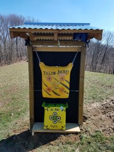 a yellow jacket sign in the middle of a field with trees and grass behind it