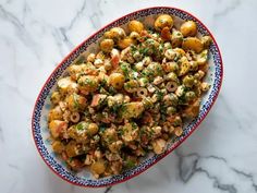 a bowl filled with food sitting on top of a marble countertop next to a knife and fork