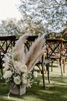 an arrangement of flowers and pamodia in a vase on the grass at a wedding ceremony