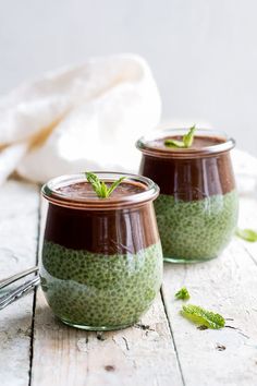 two jars filled with green food sitting on top of a wooden table next to each other