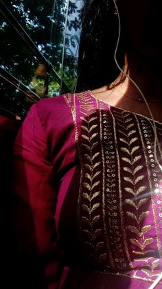 the back of a woman's pink blouse with gold and white designs on it