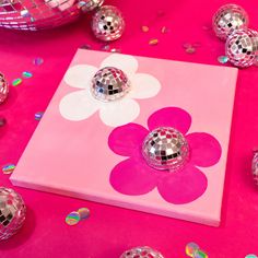 disco balls are scattered around a pink square with a flower on the front and center