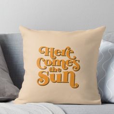 a pillow with the words here comes the sun on it in orange and yellow colors