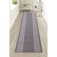 a gray and white runner rug on the floor in front of a book shelf filled with books