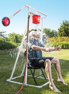 a man sitting in a lawn chair playing with a water sprinkler