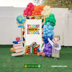 there is a welcome back to school sign and balloon arch on the lawn with books