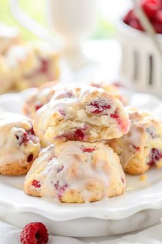 raspberry scones on a white plate with fresh raspberries in the background