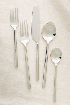 five forks, two spoons and one knife on a white cloth