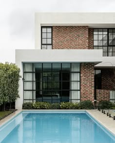 an empty swimming pool in front of a modern house