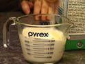 a person mixing something in a blender on a counter top next to a carton of pyrex