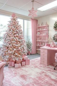 a pink and white christmas tree sitting in a room next to a desk with presents on it