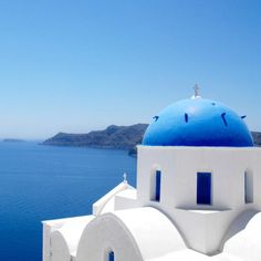 a blue dome on top of a building next to the ocean with white walls and windows