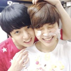 two young boys are smiling while they have cake on their faces and one is covering his face with the other's hair