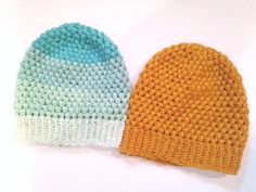 two crocheted hats sitting next to each other on a white surface, one blue and the other orange