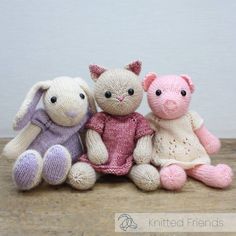 three knitted stuffed animals sitting next to each other on a wooden floor with a white wall in the background