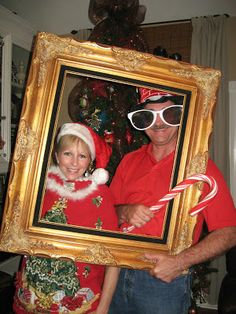 a man and woman in christmas attire holding up a framed photo with candy canes