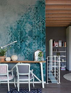 a living room with a table and chairs in front of a wall painted with blue flowers