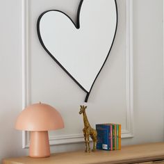 a giraffe figurine next to a lamp and a heart shaped wall decoration