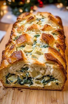 a loaf of spinach and cheese bread on a cutting board next to a christmas tree