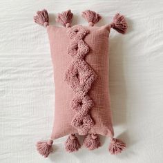 a pink pillow with tassels on it