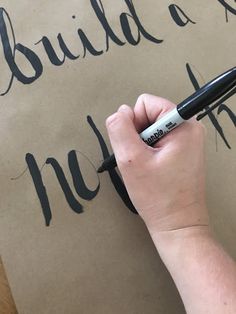 a person writing on a piece of paper with a marker